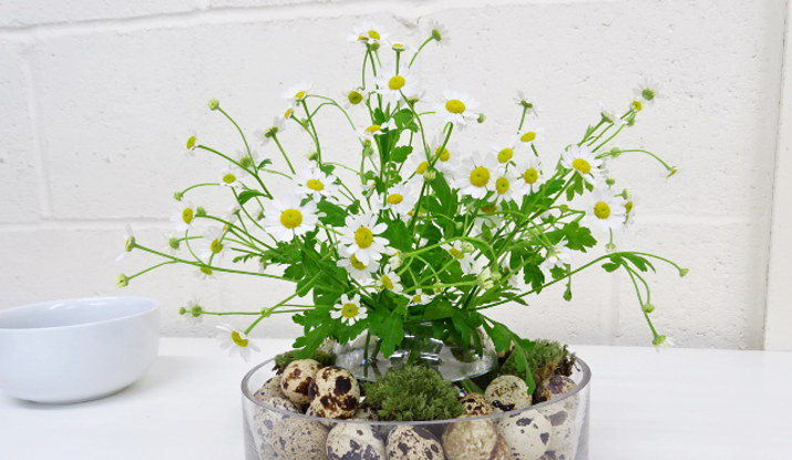 Now, you can start creating the arrangement in the centre. Start by placing the ‘intermediate’ flowers, the Tanacetum and Forget Me Not’s (Myosotis) into the vase to create a frame for the next step.