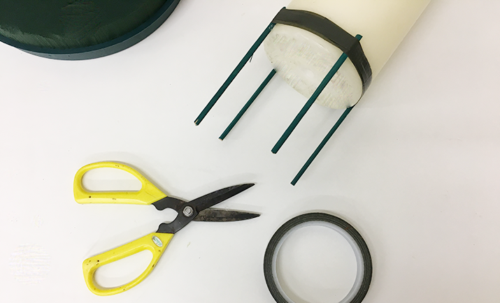 Next, secure the candle to the posy pad. You will need to cut a plant stick into 4 segments. Attach each segment to the base of the candle evenly with anchor tape (as shown in the photograph).