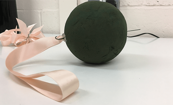 Prepare the floral foam sphere. Soak the foam in water until fully absorbed (approximately 30 seconds for the entire sphere). Attach the ribbon to the sphere - wire a loop of ribbon on sufficiently long wires that will protrude through to the base of the sphere.