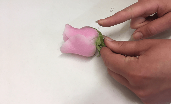 Simply, cut the rose wire into short segments and bend to create a hairpin. Push the hairpin into each sepal and into the rose. 